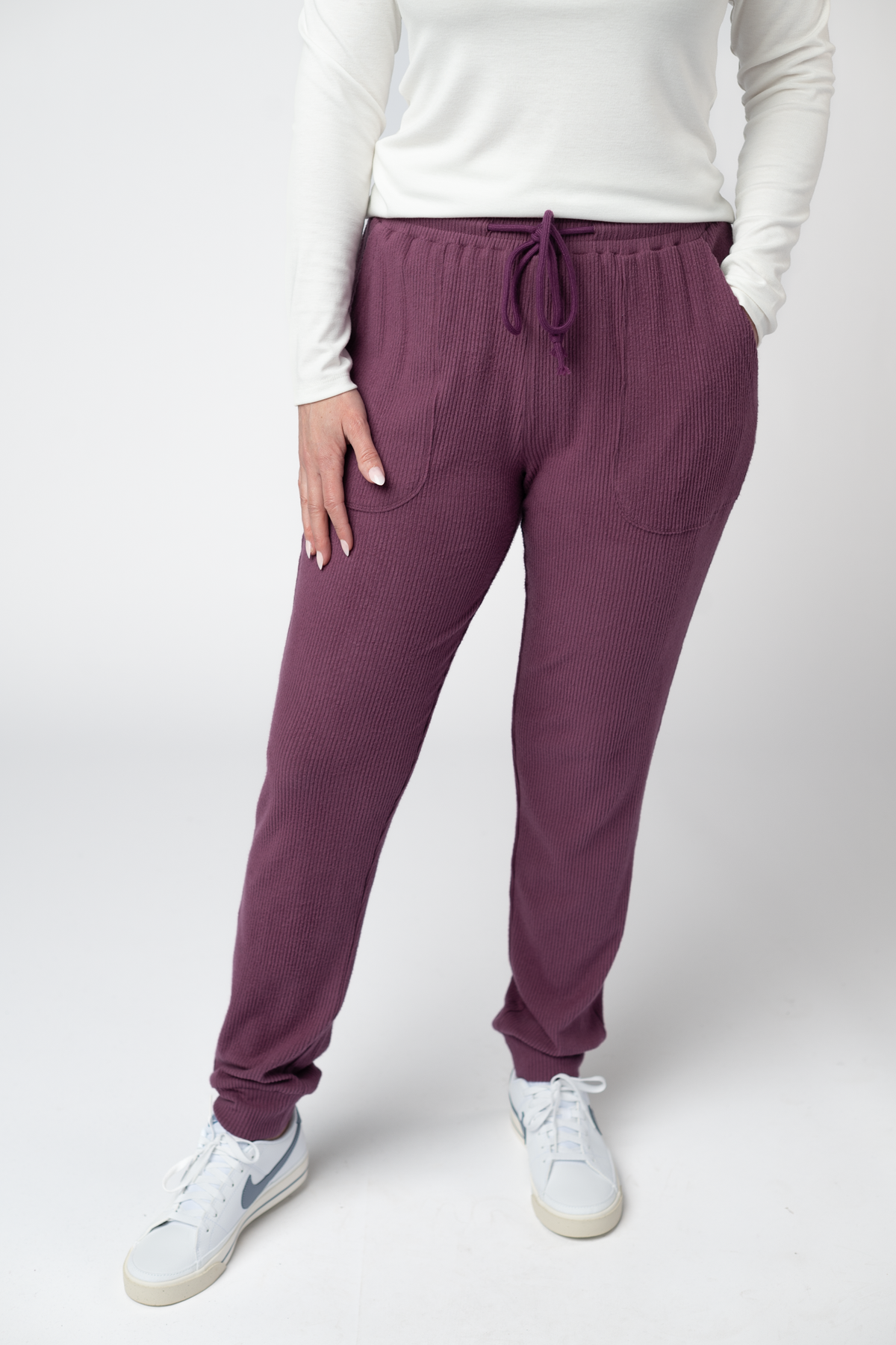 Person wearing purple jogger pants and white sneakers on a white background