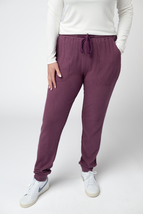 Person wearing purple jogger pants and white sneakers on a white background