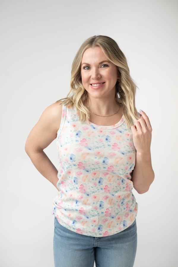 Woman wearing a floral tank top and jeans against a white background