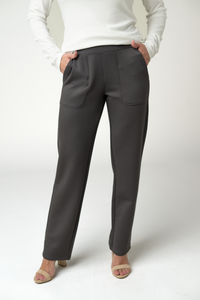 Person wearing gray pants and a white top on a plain background