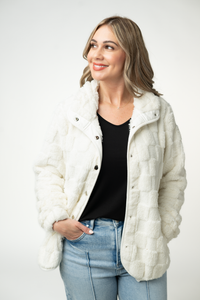 Woman wearing a white quilted jacket with a plain background