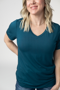 Woman wearing a teal V-neck t-shirt against a plain background