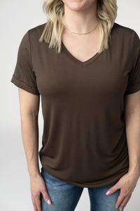 Person wearing a brown t-shirt and blue jeans on a plain background