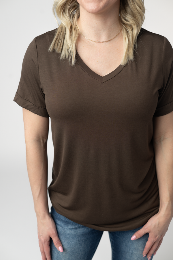 Person wearing a brown t-shirt and blue jeans on a plain background