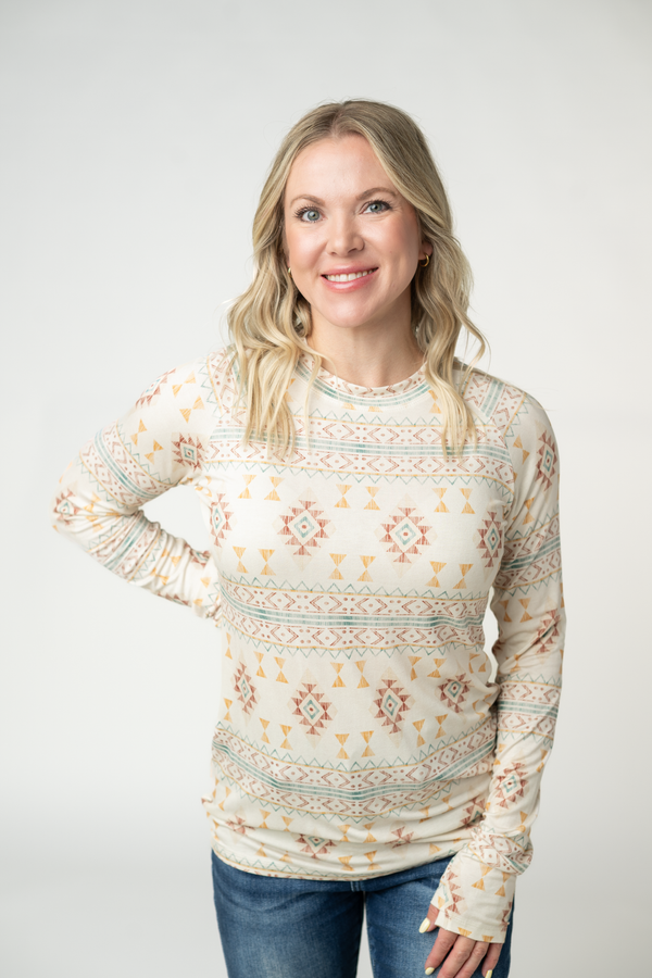 Woman wearing a patterned long-sleeve top against a plain background