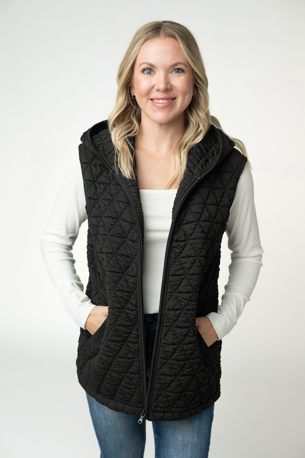 Woman wearing a black quilted vest on a white background