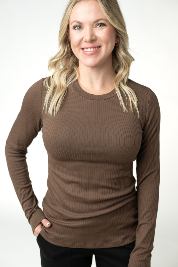 Woman wearing a brown ribbed long-sleeve top against a white background
