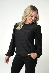 Woman wearing a black textured blouse with long sleeves on a white background