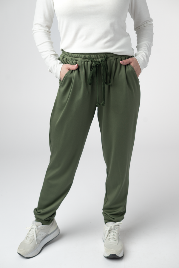 Person wearing green jogger pants and white sneakers on a white background