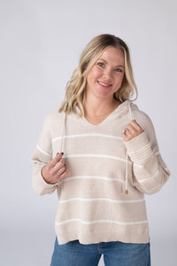 Woman wearing a beige striped sweater against a white background