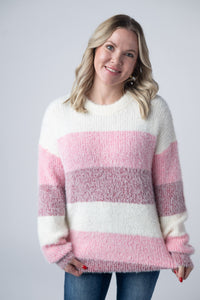 Woman wearing a pink and white striped sweater against a plain background