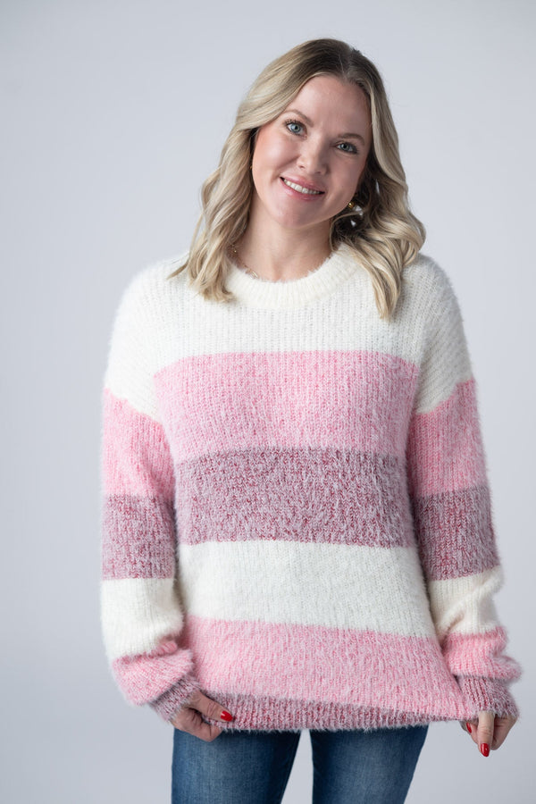 Woman wearing a pink and white striped sweater against a plain background