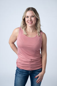Woman wearing a pink tank top and blue jeans against a white background