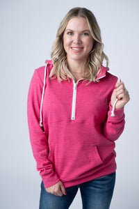 Woman wearing a pink hoodie with a white zipper on a plain background