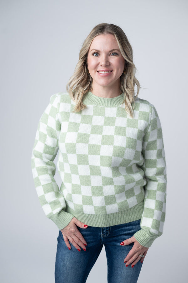 Woman wearing a green and white checkered sweater against a plain background