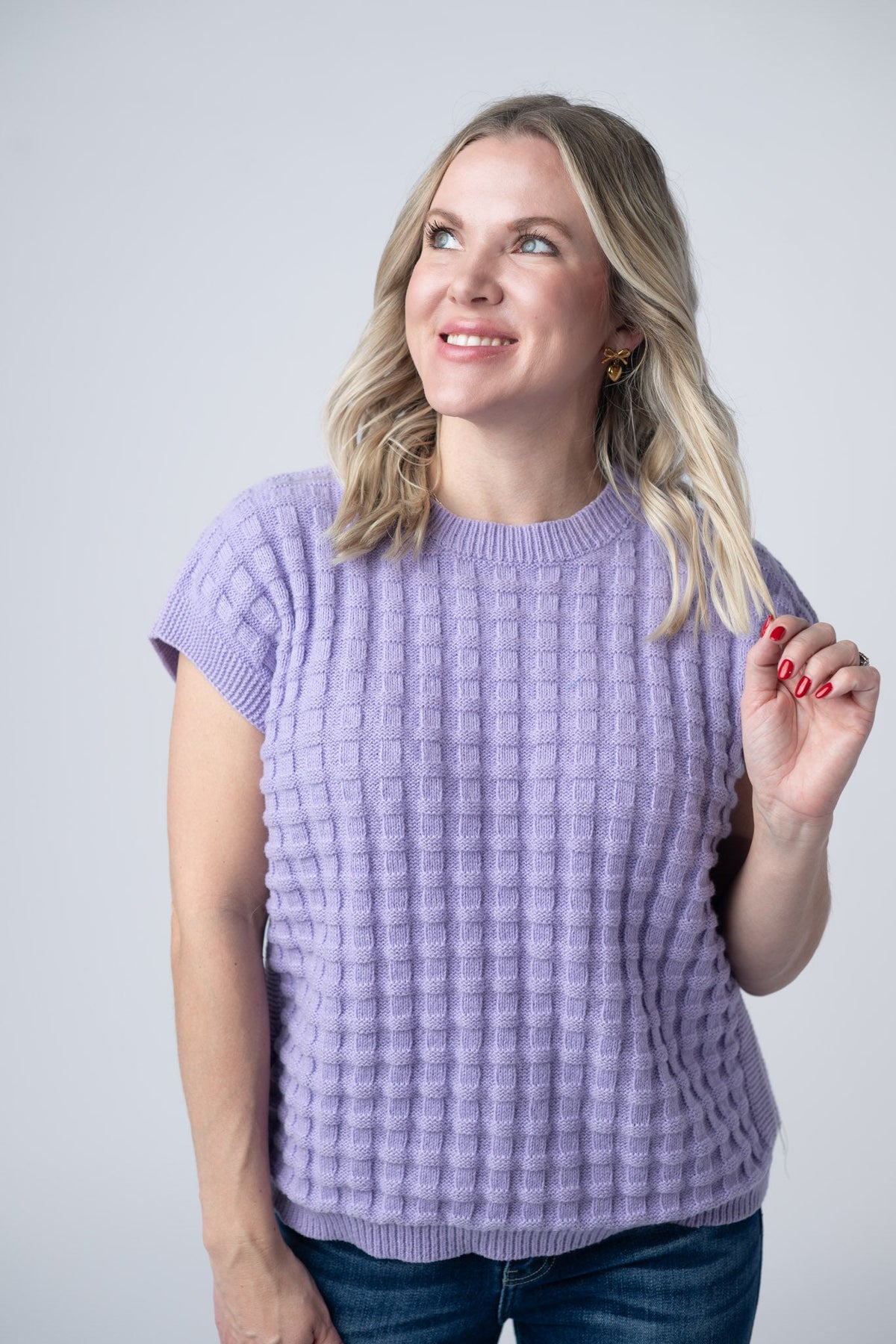 Woman wearing a light purple knitted top against a plain background