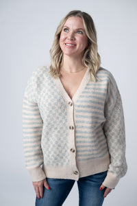 Woman wearing a patterned cardigan against a plain background