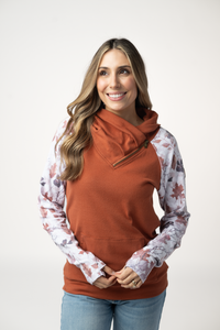 Woman wearing a rust-colored top with floral sleeves on a white background