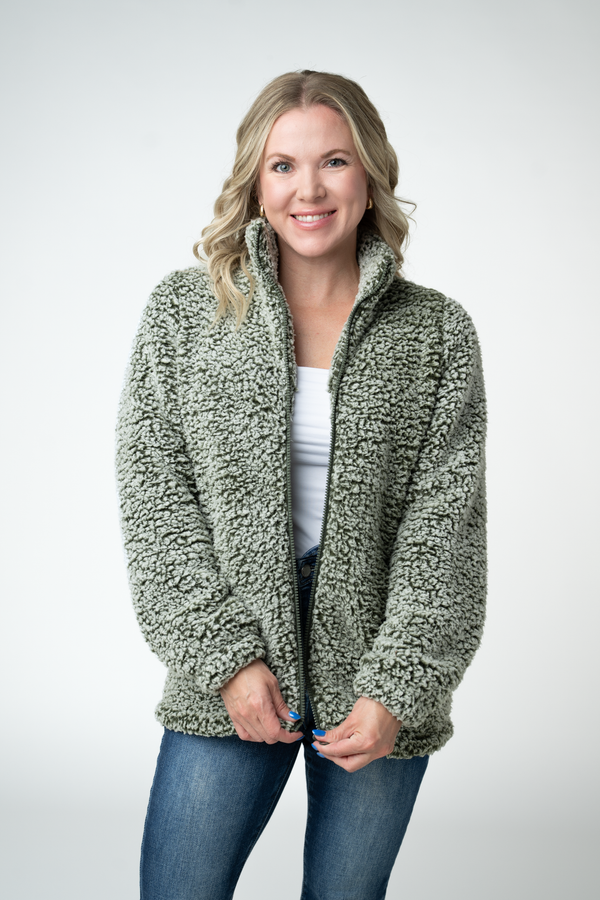 Woman wearing a green sherpa jacket on a white background