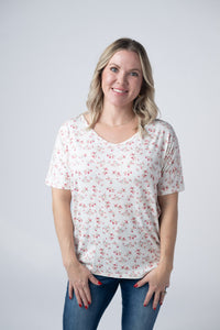 Woman wearing a white floral blouse against a plain background