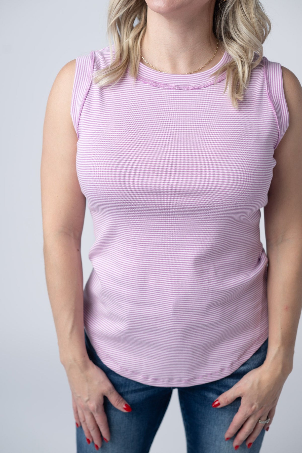 Person wearing a pink striped sleeveless top against a plain background