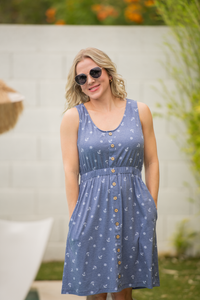 Woman wearing a blue dress with a floral pattern outdoors.