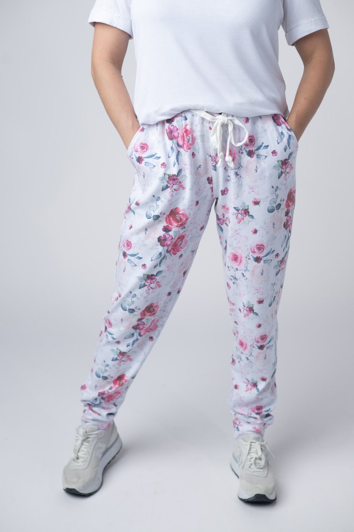 Person wearing floral pajama pants and a white t-shirt on a plain background