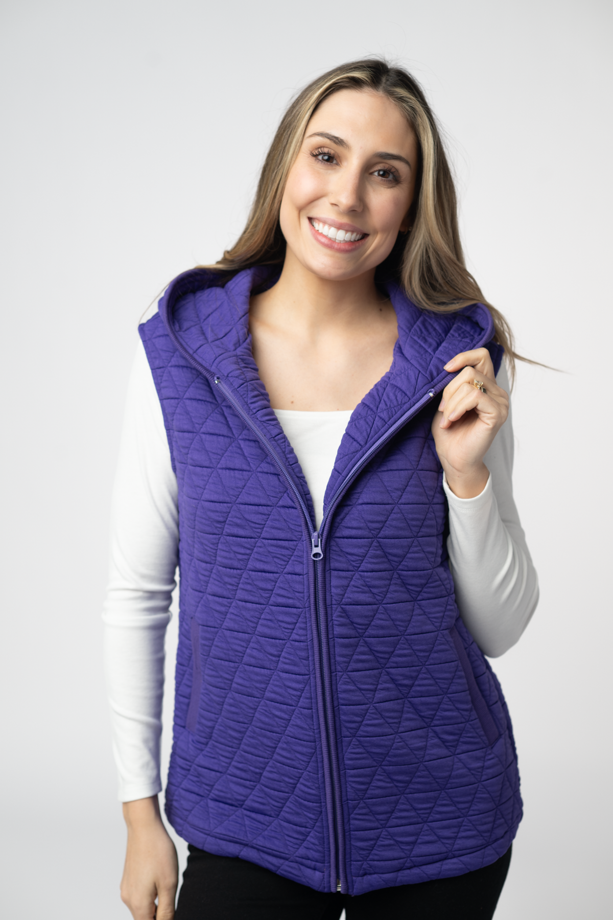 Woman wearing a purple quilted vest against a white background
