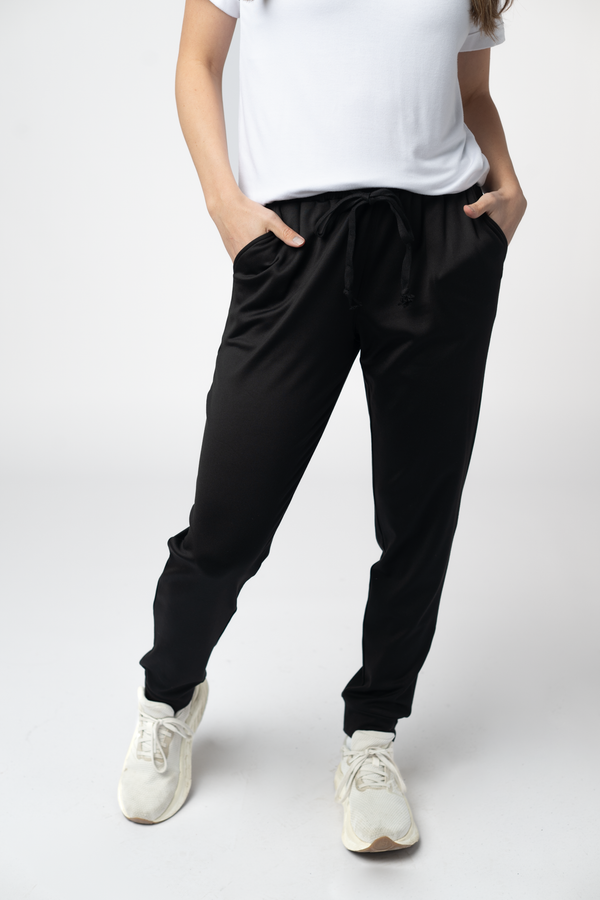 Person wearing black pants and white sneakers on a white background
