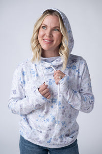 Woman wearing a floral-patterned hoodie against a plain background
