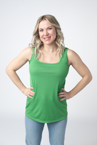 Woman wearing a green tank top and blue jeans on a white background