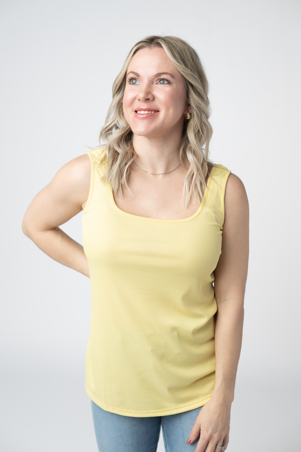 Woman wearing a yellow tank top against a white background