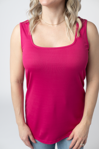 Woman wearing a bright pink tank top against a plain background
