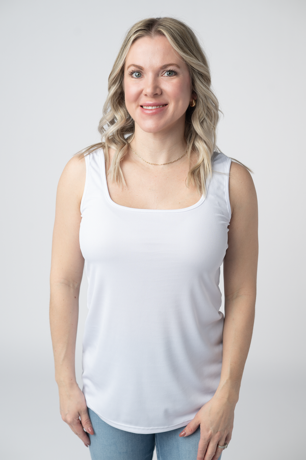 Woman wearing a white tank top against a plain background