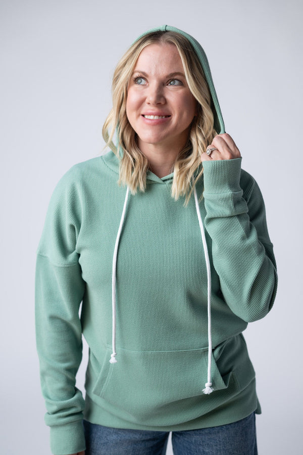 Woman wearing a green hoodie against a plain background