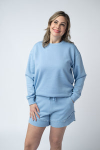 Woman wearing a light blue sweatshirt and shorts set on a white background