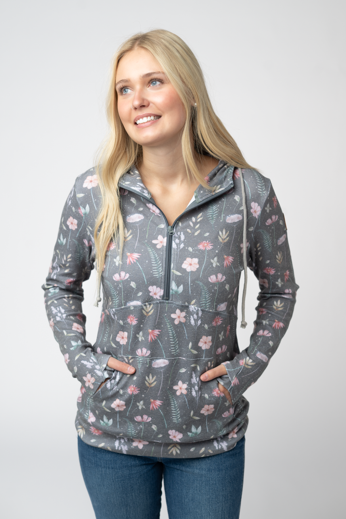 Woman wearing a floral patterned gray pullover with a white background