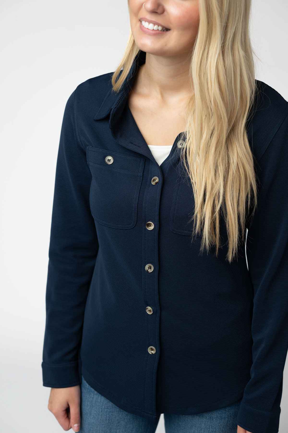 Woman wearing a navy blue button-up shirt against a white background