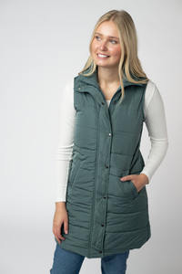Woman wearing a green puffer vest on a white background