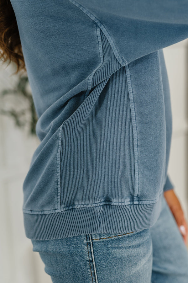 Close-up of a person wearing a blue sweatshirt and jeans with a blurred background