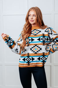 Woman wearing a patterned sweater against a white tiled wall