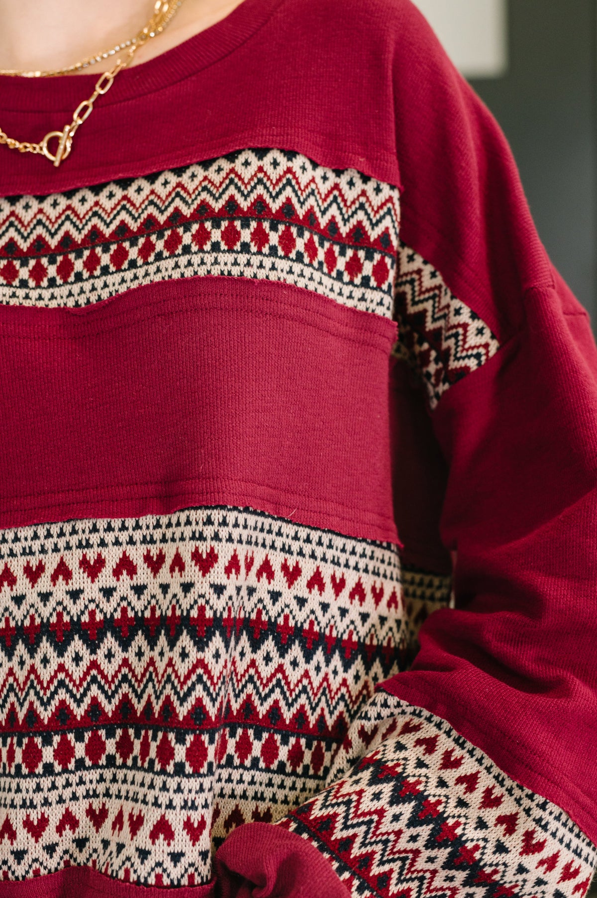 Close-up of a red sweater with patterned sleeves and hem.