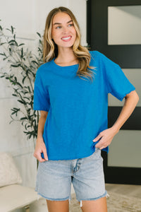 Woman wearing a blue t-shirt and denim shorts indoors