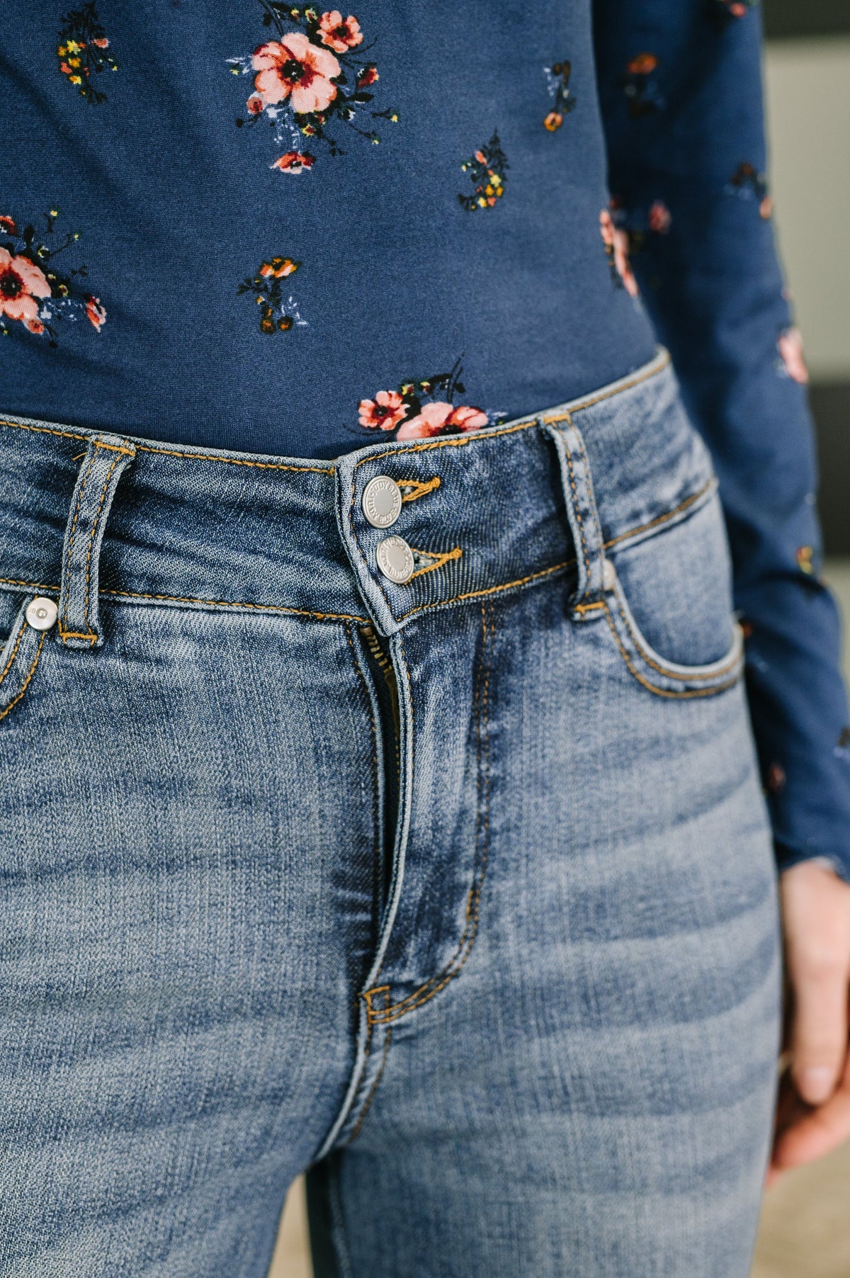 Close-up of blue jeans with floral patterned top