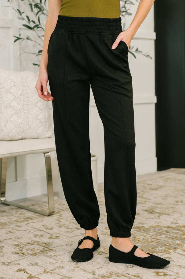 Person wearing black jogger pants in a home setting