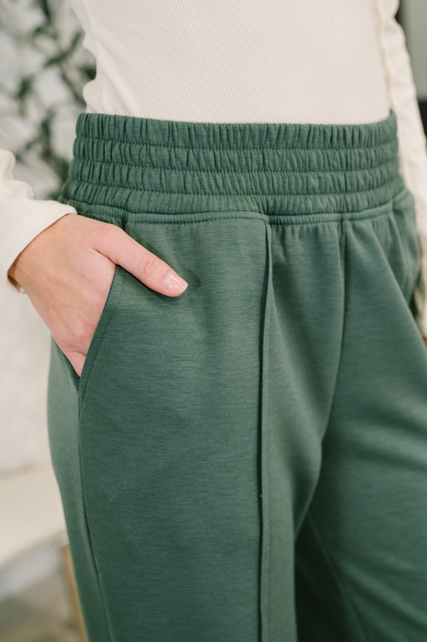 Green sweatpants worn by a person with a blurred background