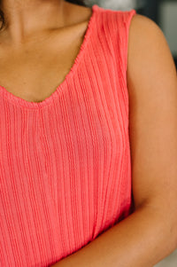 Close-up of a person wearing a pink sleeveless dress.