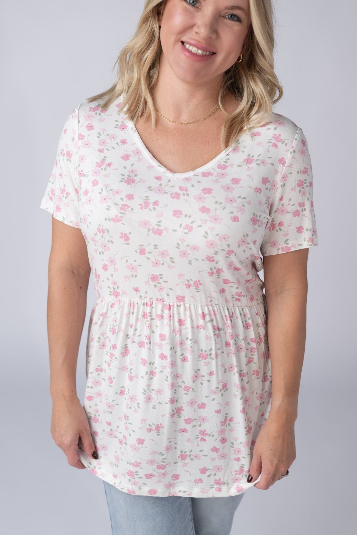Woman wearing a white t-shirt with pink floral pattern on a plain background