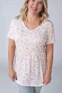 Woman wearing a white t-shirt with pink floral pattern on a plain background