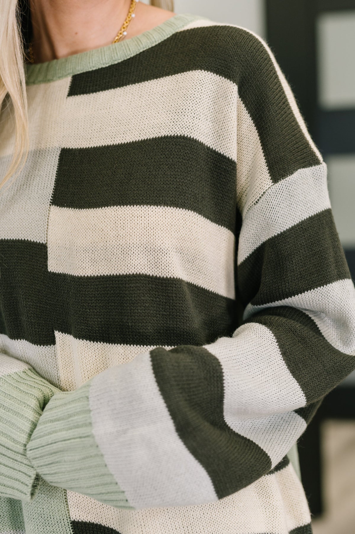 Close-up of a person wearing a green and beige striped sweater.